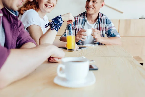 Amigos bebiendo bebidas y hablando en la cafetería — Foto de Stock