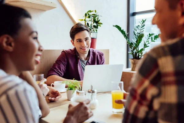 Multiethnic friends with laptop and beverages — Stock Photo, Image