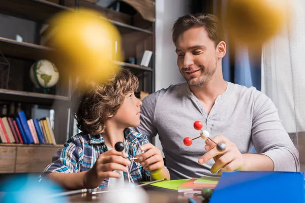 Padre e hijo jugando con el modelo de átomos — Foto de stock gratis