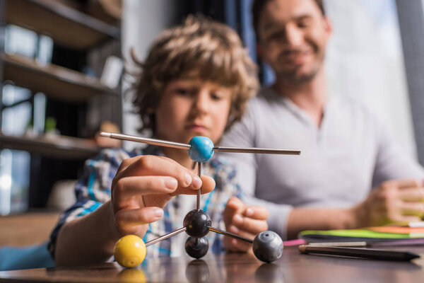 father and son playing with atoms model
