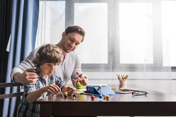 Отец и сын играют с моделью атомов — стоковое фото