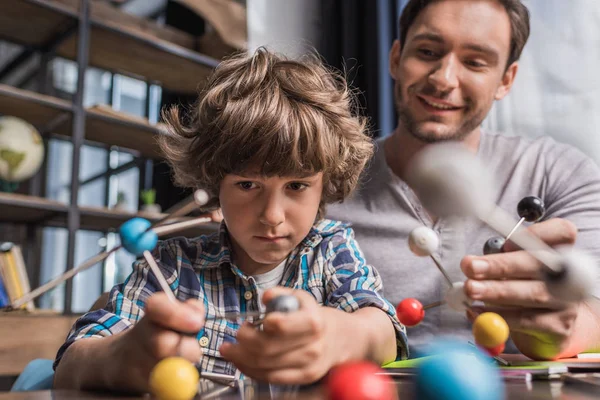 Отец и сын играют с моделью атомов — стоковое фото