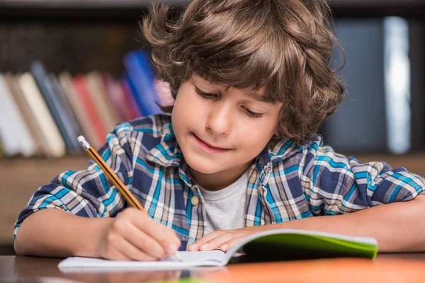 Kid writing in copybook — Stock Photo, Image