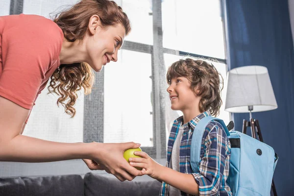 Mother giving apple to son — Stock Photo, Image