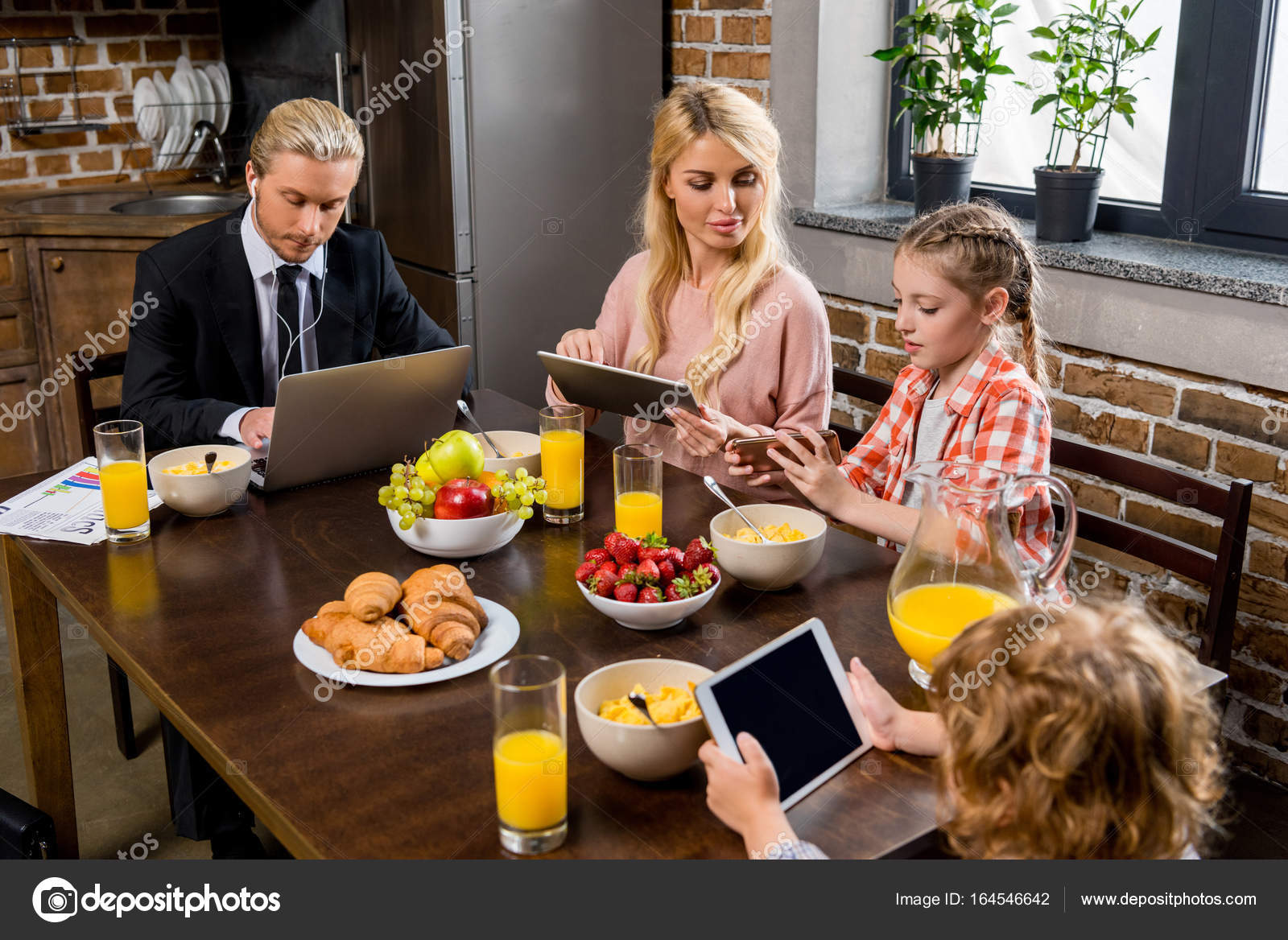 Family using gadgets at breakfast Stock Photo by ©AlexLipa 164546642