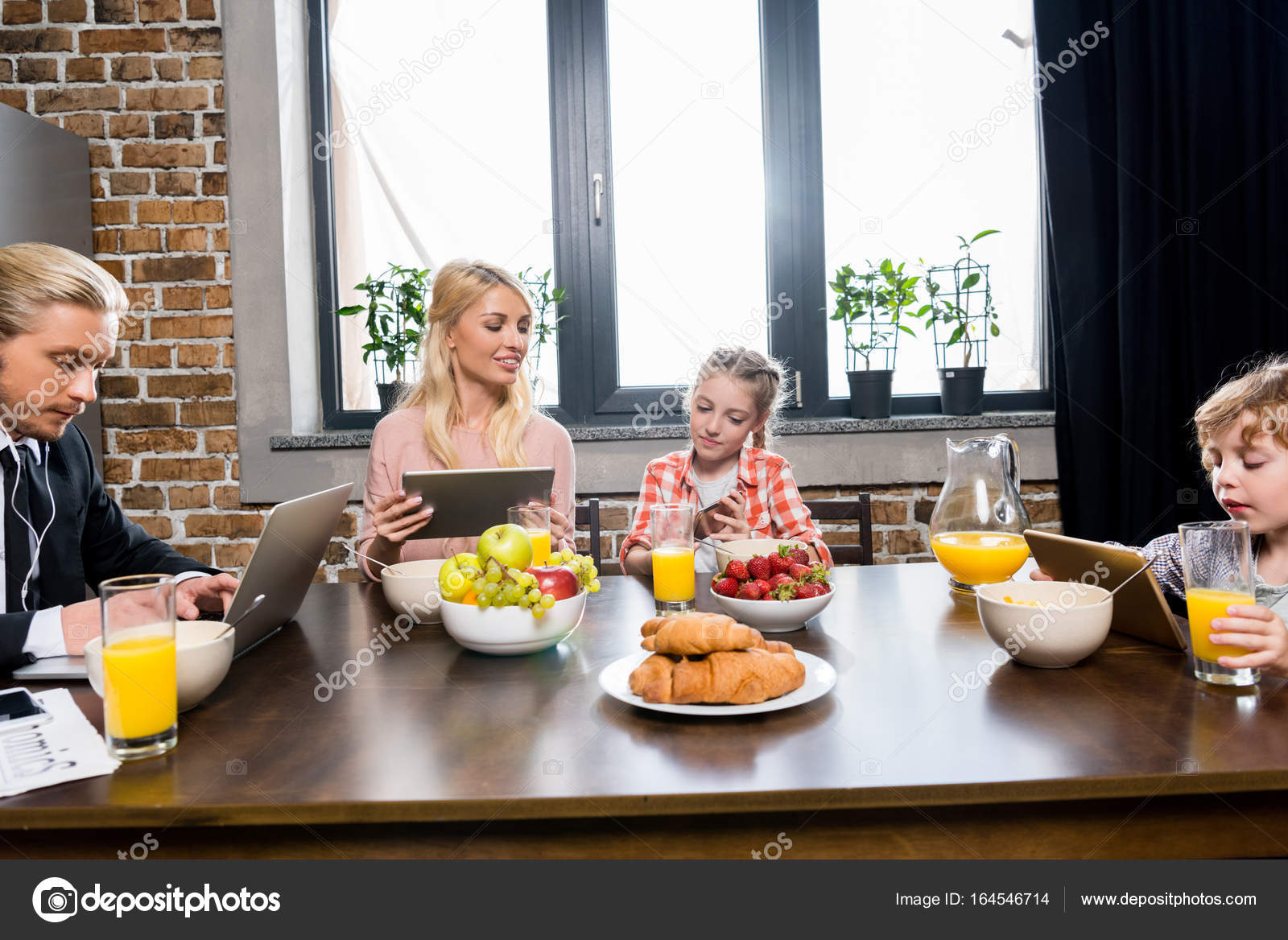 Family using gadgets at breakfast Stock Photo by ©AlexLipa 164546714