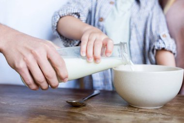 father with child pouring milk clipart