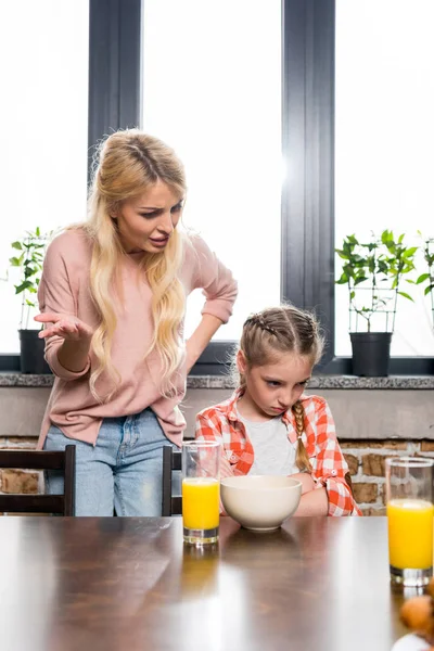 Mother feeding daughter at breakfast — Stock Photo, Image