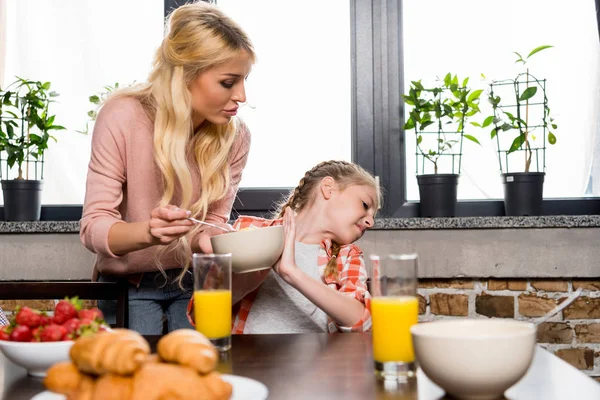 Mother feeding daughter at breakfast — Stock Photo, Image