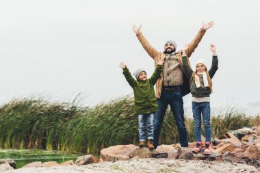 father and kids wih raised hands outdoors clipart