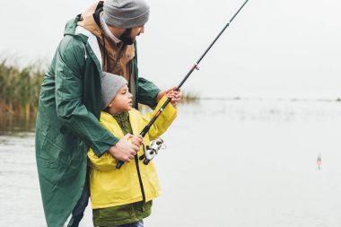 Baba ve oğul birlikte balık tutuyorlar.