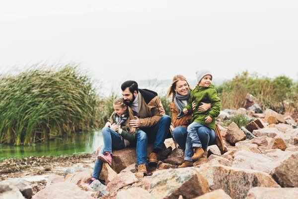 Семья, сидящая на скальном побережье — стоковое фото