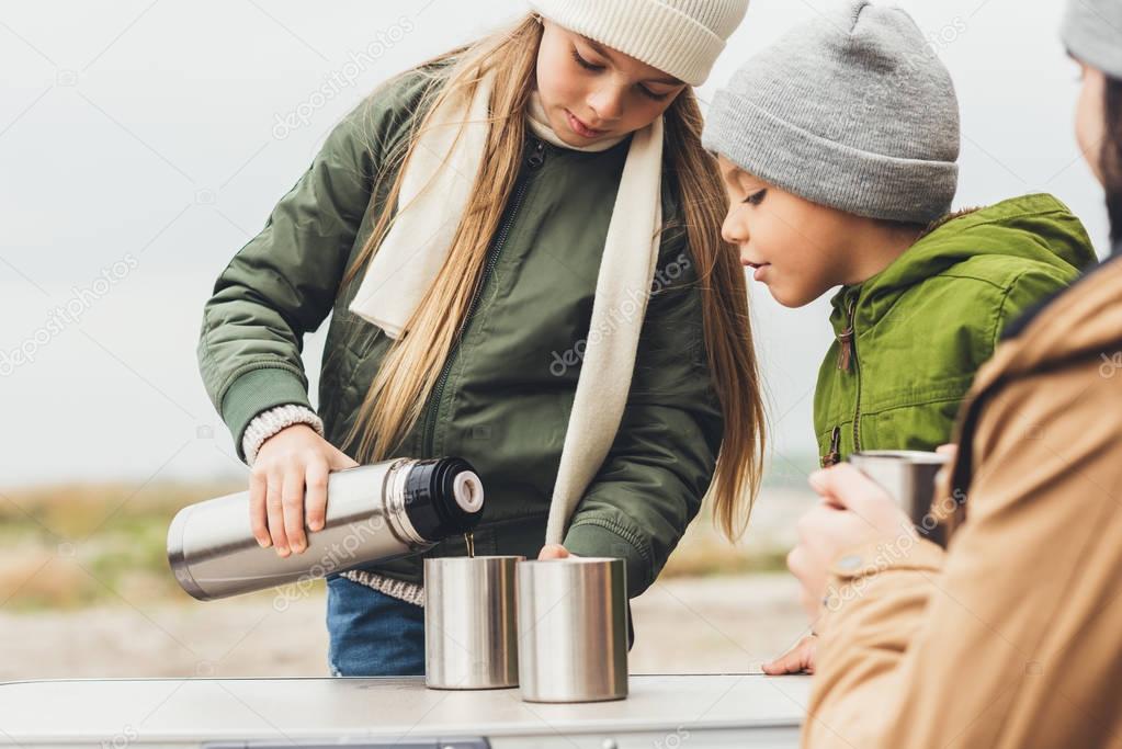 girl pouring tea for brother and father