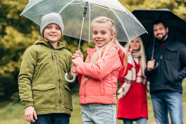 Parents and kids with umbrellas — Stock Photo, Image