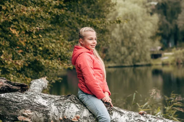 Child sitting on log in park — Free Stock Photo