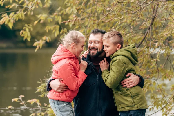 Felice padre e figli che si abbracciano nel parco — Foto Stock