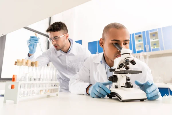 Cientista que trabalha com microscópio — Fotografia de Stock