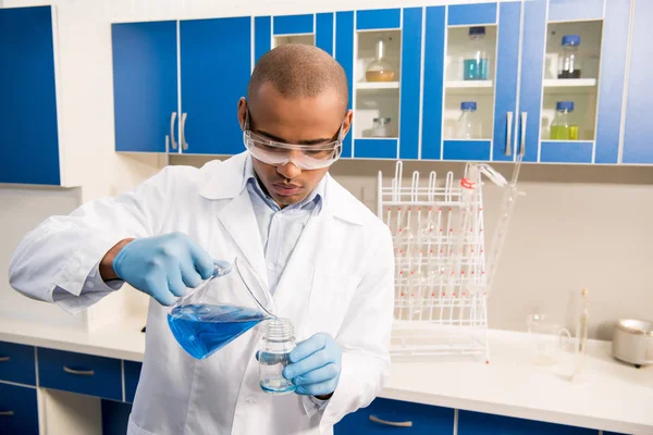 Scientist pouring reagent into jar — Free Stock Photo