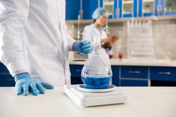 Scientist weighing flask with reagent — Stock Photo, Image
