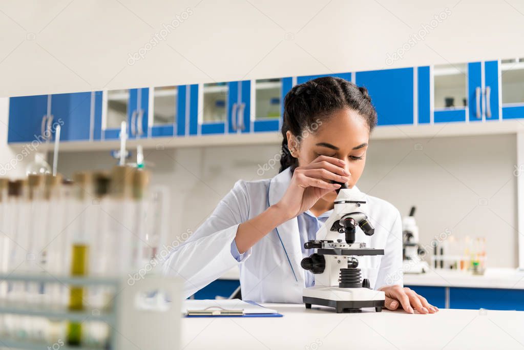technician using microscope in laboratory