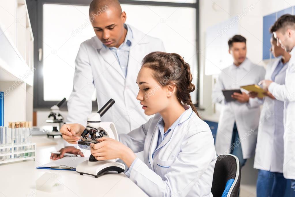 Chemists working with microscope