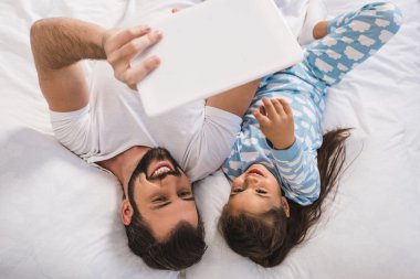 Baba ve kızı yatakta tablet kullanma