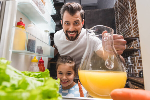 father and daughter taking juice from fridge