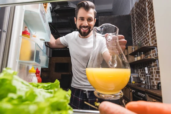Мужчина достает сок из холодильника — стоковое фото
