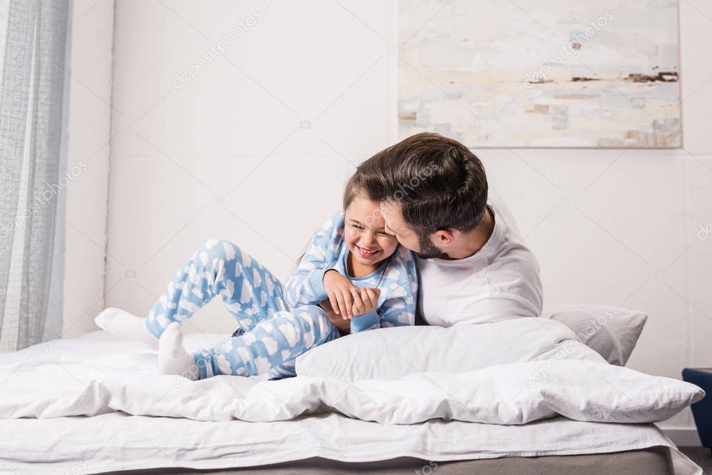 father and daughter cuddling in bed