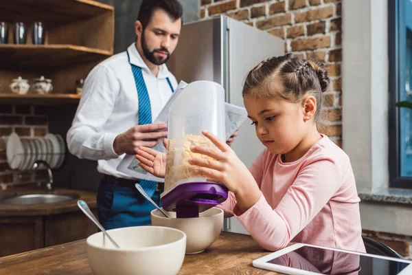 Daughter pouring cereal in bowl for father — Free Stock Photo