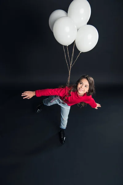 Ребенок имитирует полет с воздушными шарами — стоковое фото