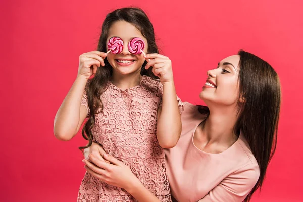 Daughter covering eyes with lollipops — Stock Photo, Image