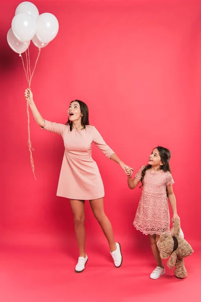 Mãe e filha olhando para balões de hélio — Fotografia de Stock