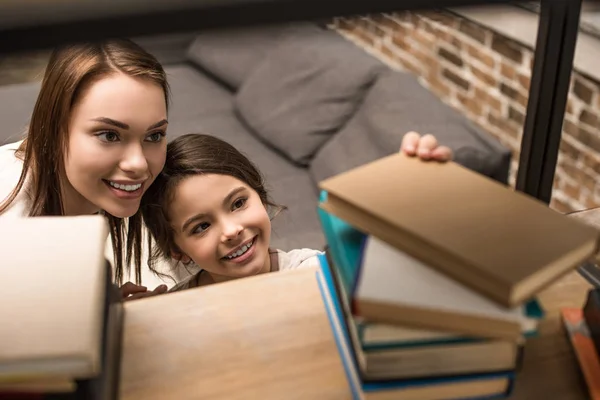 Daughter taking book from bookshelf — Stock Photo, Image