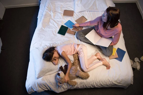 Hija durmiendo y madre trabajando por la noche — Foto de stock gratis