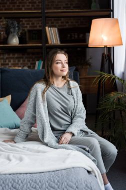 güzel genç kadın yatağa sabah oturma ve uzağa arıyorsunuz