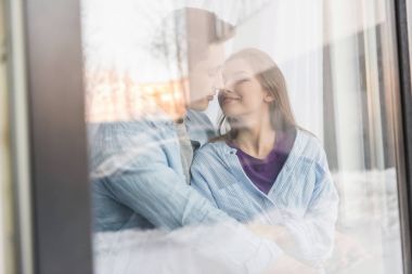view through window on couple going to kiss with closed eyes clipart