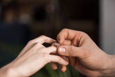 cropped image of boyfriend proposing girlfriend and wearing engagement ring clipart