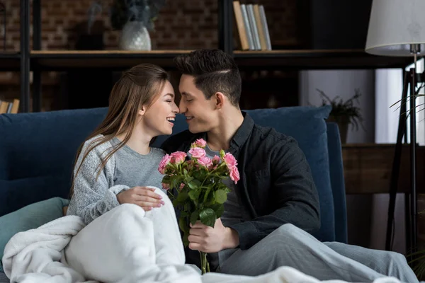 boyfriend presenting bouquet of roses to happy girlfriend on international womens day