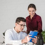 Young managers reading notes together at workplace in modern office