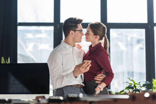 attractive kissing young businesspeople in formal clothing having office romance