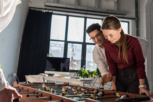 happy business partners playing table football together as team