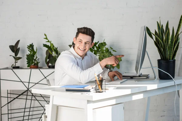 Glücklicher Junger Geschäftsmann Zeigt Auf Computerbildschirm Stockfoto