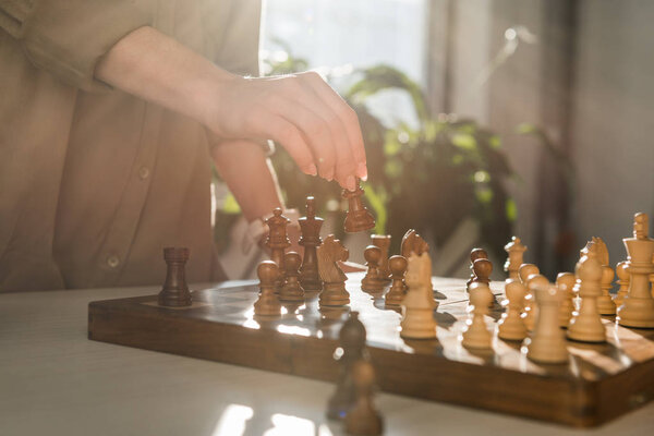 cropped shot of woman making move while playing chess