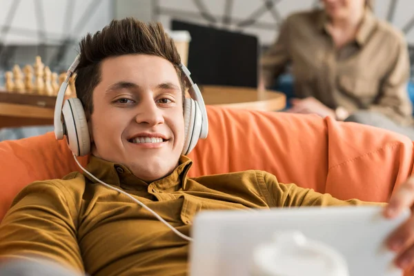 微笑的年轻人放松与平板电脑和耳机 — 图库照片
