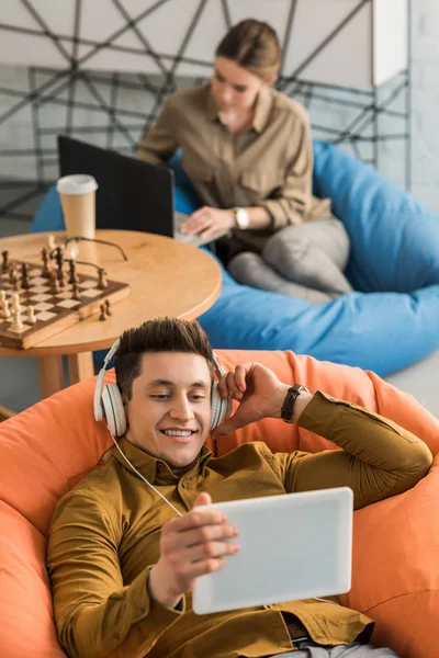 Jovem Ouvindo Música Com Tablet Fones Ouvido Enquanto Sentado Saco — Fotos gratuitas