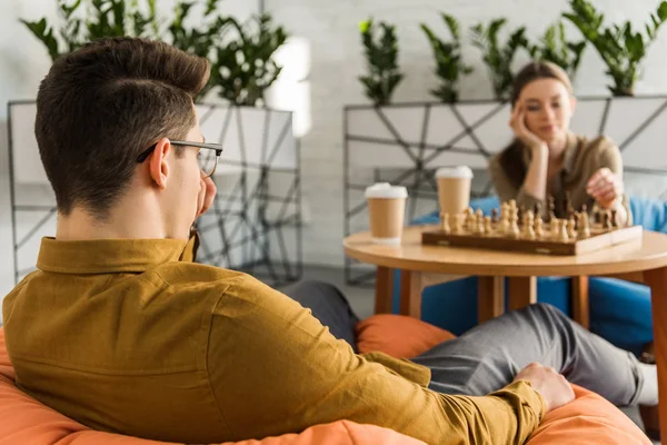 लक्ष केंद्रित तरुण पुरुष आणि स्त्री बुद्धिबळ खेळत स्टॉक इमेज