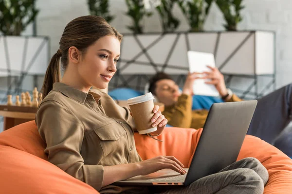 Wanita Muda Minum Kopi Dan Bekerja Dengan Laptop Sambil Duduk Stok Gambar