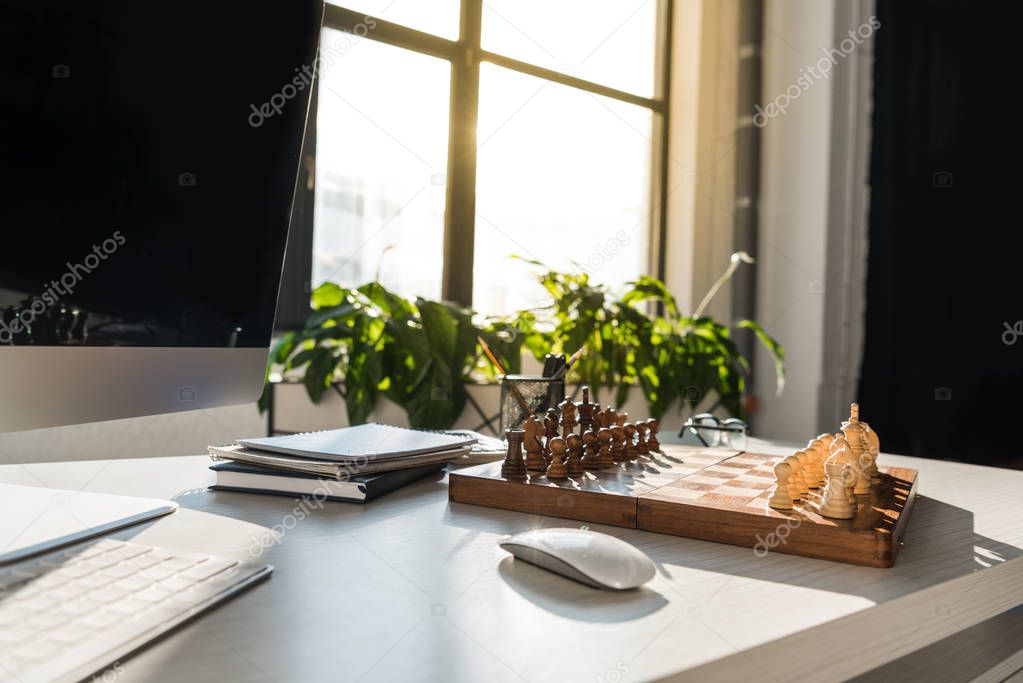 close-up shot of chess board at modern workplace with computer