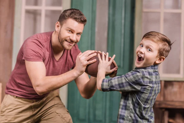 Отец с сыном играют с мячом на заднем дворе — стоковое фото